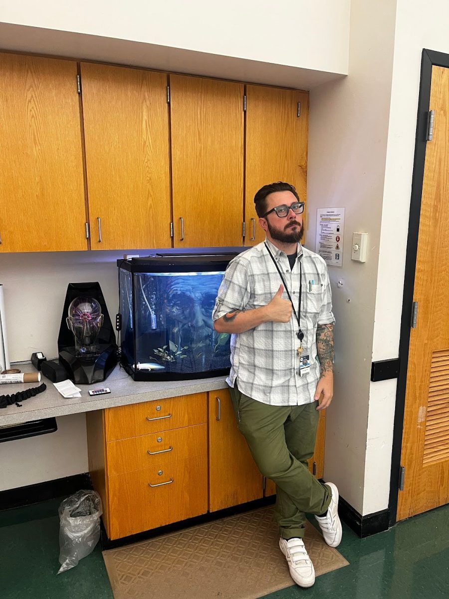 Caption: (Scott Sowers, in his classroom next to his axolotl.)