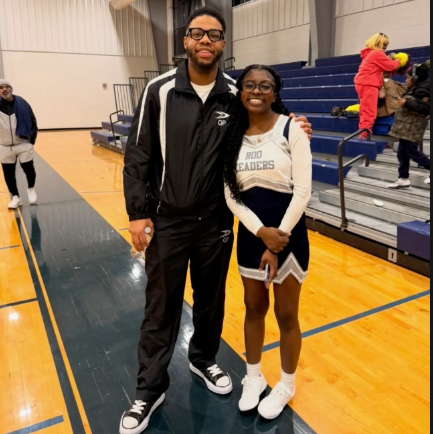 Madison Younger-McLaurin '27, student and team manager of the RooLeaders, wears the team uniform while standing beside her brother, Mikael Green. 